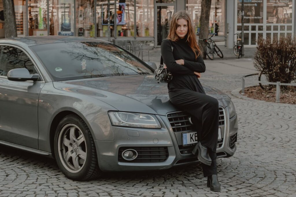 Woman in Black Clothes Sitting on Gray Audi Car